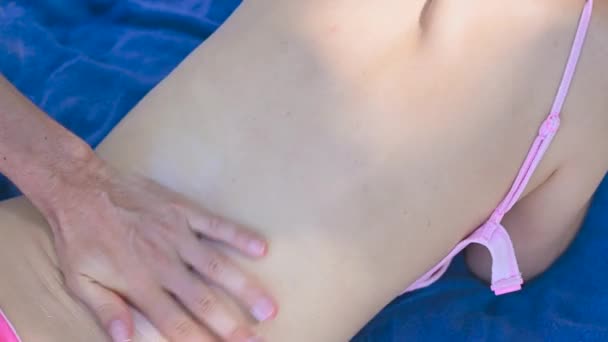 Gros plan d'un homme mains appliquant une lotion bronzante sur le dos des femmes, homme mettant crème bronzante crème solaire sur une plage — Video