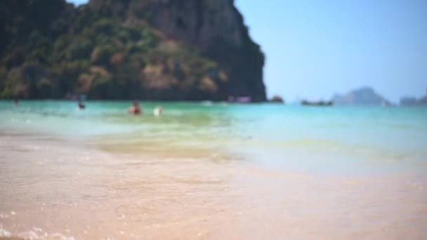 Vista de cerca de las olas del océano turquesa rodar en la costa pacífica en la isla tropical. Personas descansando en agua tibia en una playa durante las vacaciones de verano . — Vídeos de Stock