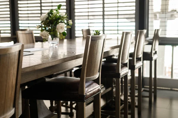 Lege houten stoelen met leren vulling staan rondom tafels in restaurant — Stockfoto