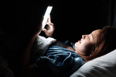 Genç Asyalı kadın smartphone yatağa gece geç saatlerde kullanarak. Sağlık kavramı