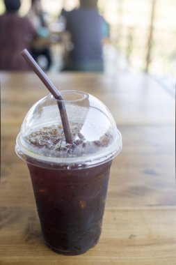 Americano kahve ahşap bir masa üzerinde plastik bir kap içinde.