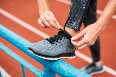 Bağcıklarını bağlayan koşucu, stadyumda koşmaya hazırlanıyor.