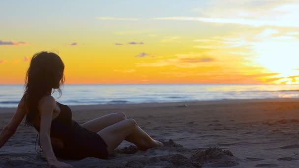女人引诱和愉快地滚动沿着沙滩上的沙子 轻轻地笑 从附近和背景 海洋和日落的环境可以看到 — 图库视频影像