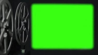 Super 8 sinema projektörü karanlık odada yeşil ekran gösteriyor.