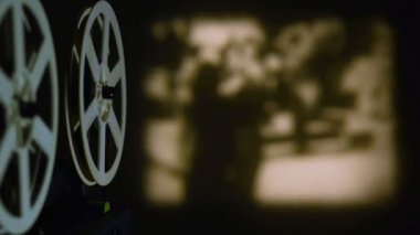 Sinema projektörü, karanlık bir odada süper 8 formatında sepya tonunda bir film gösterir..
