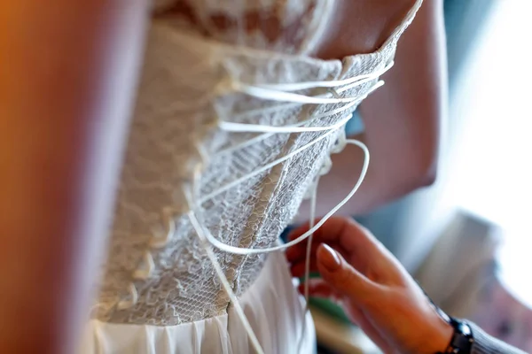 Mother helping her daughter get dressed for wedding.