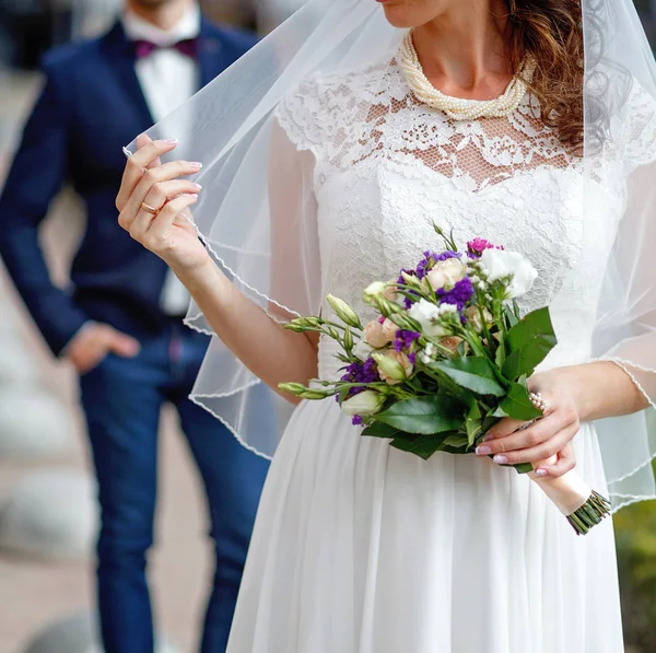 Noiva em véu de renda segurando um buquê de casamento — Fotografia de Stock