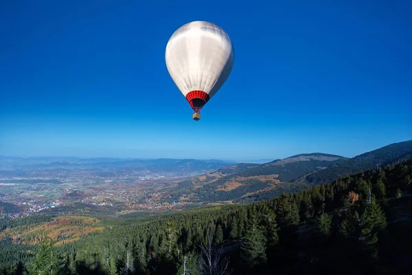 High balloon flight .Balloon flight with a basket filled with people on a background of blue sky. Aerial view of city at foot of green hills . Sky and mountain views nature