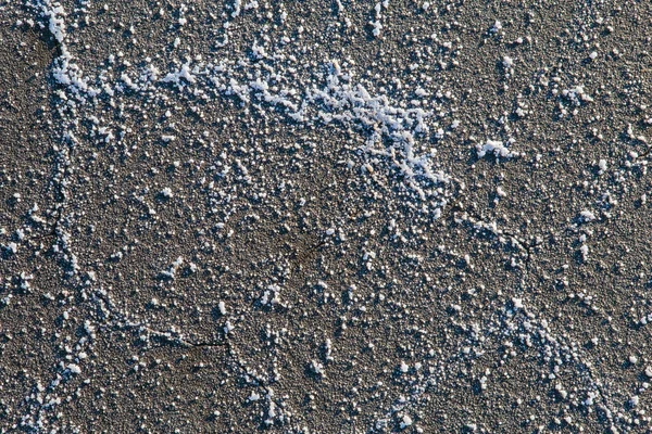 De textuur van het oppervlak van de zout-gebarsten kust dat heeft gekraakt, met grote kristallen zout. — Stockfoto