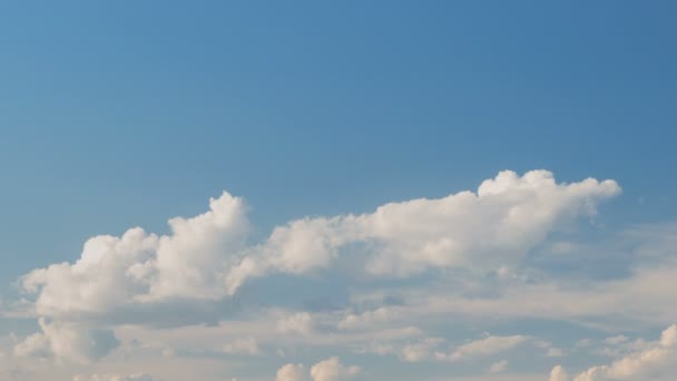 Vorming en snelle beweging van de witte wolken van verschillende vormen in de blauwe lucht in het late voorjaar bij zonsondergang. — Stockvideo