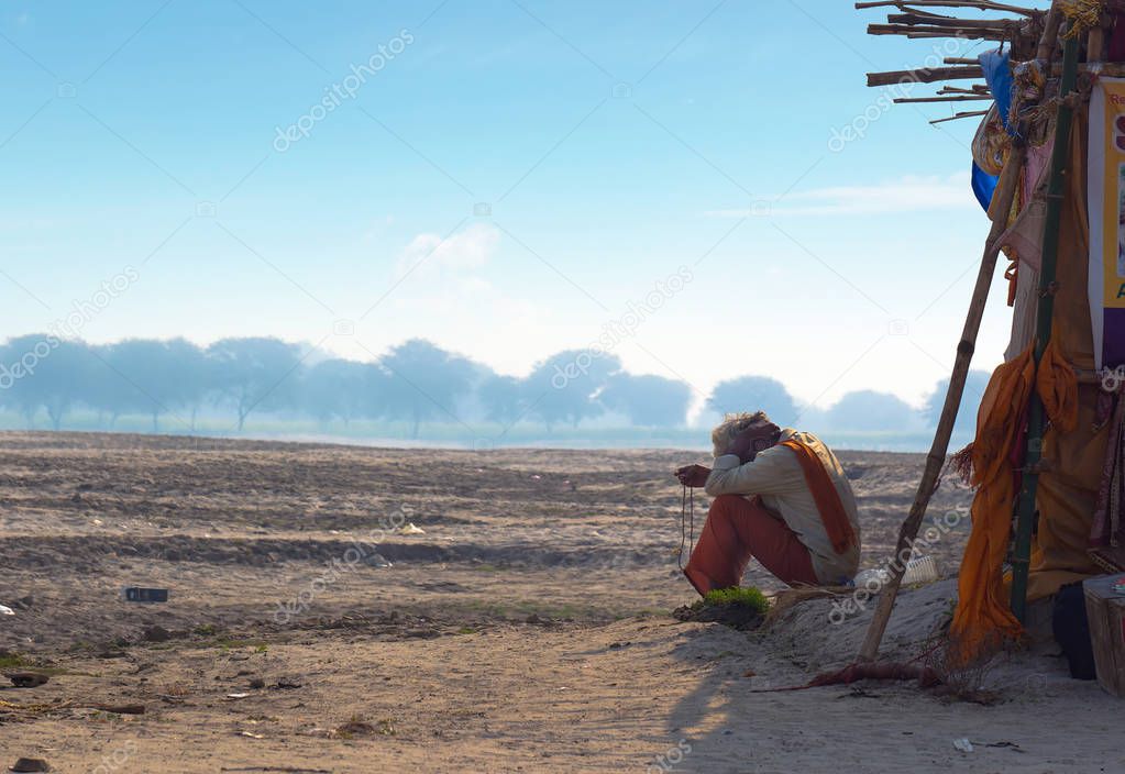 The hermit, a sadhu, sits meditating on the Holy river Ganges