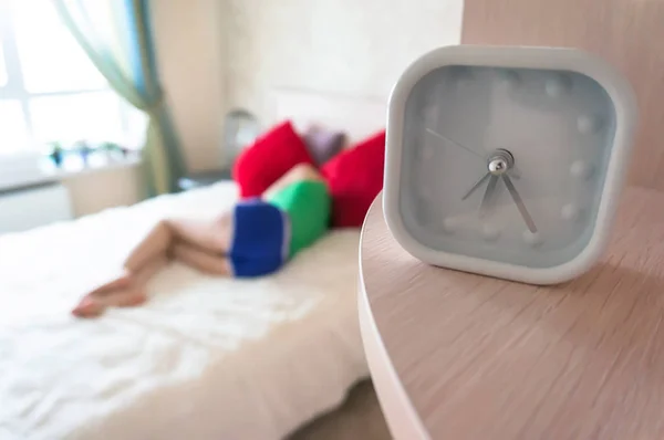 Reloj despertador blanco en el fondo de dormir en la cama chica por la mañana temprano . — Foto de Stock
