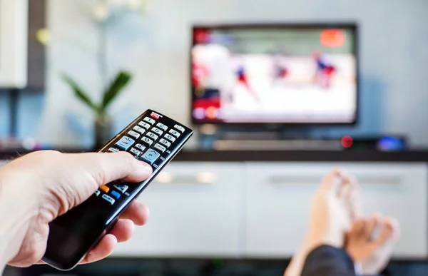 Mannen met de afstandsbediening, voorzijde van de televisie. — Stockfoto