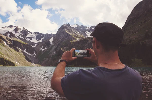 Manos de hombre sosteniendo el teléfono móvil en el mar y las montañas — Foto de Stock