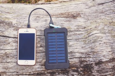 Ahşap arka plan üzerinde pembe güç banka ile şarj Smartphone