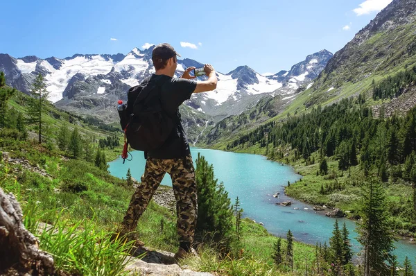 Turista toma fotos con teléfono inteligente en el pico del paisaje montañoso — Foto de Stock