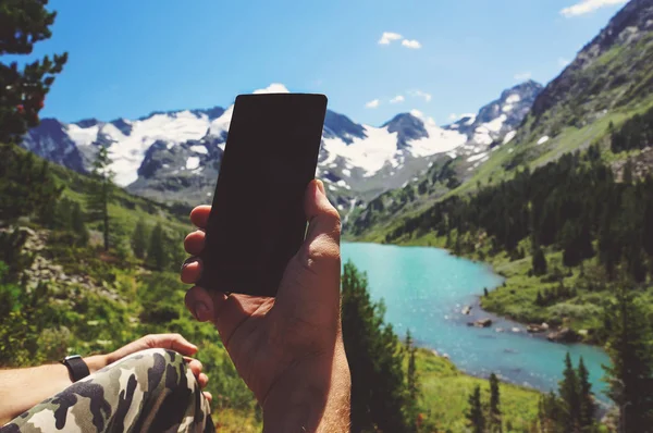 Hand mit Smartphone auf verschwommenem Landschaftsbild — Stockfoto