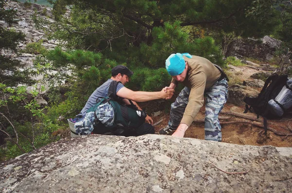 Camper helpt een ander om de rots te beklimmen. — Stockfoto
