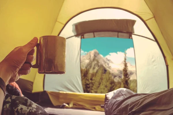 Frau liegt im Zelt mit Kaffee, Blick auf Berge und Himmel — Stockfoto