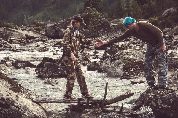 Jonge hipster mooie paar in liefde lopen op een rotsen bij de rivier in bos. — Stockfoto