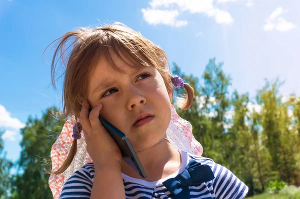 Kleines Mädchen schaut auf und spricht per Handy, — Stockfoto