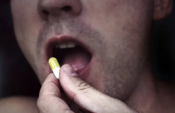 Close up man taking pill medicine