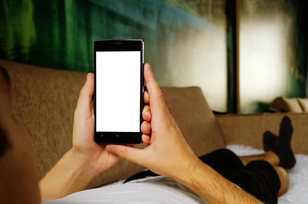 Mannen avkopplande under liggande på soffan - blank skärm smartphone — Stockfoto