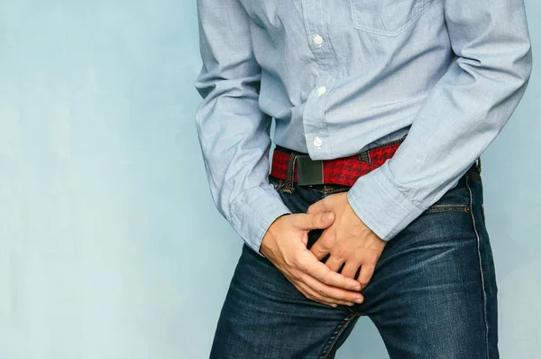 The guy in the jeans and blue shirt holding hands his crotch — Stock Image The guy in the jeans and blue shirt holding hands his crotch Royalty Free Stock Photos