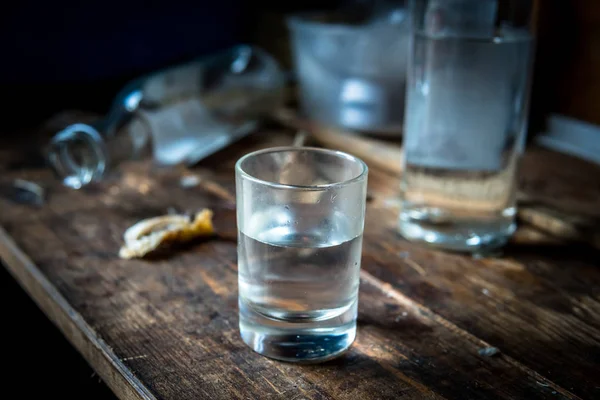 Una pequeña pila de vodka de cerca en la vieja mesa de madera sucia — Foto de Stock