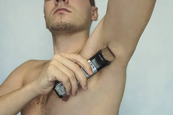 Guy met bont scheren onderarm trimmer close-up op witte geïsoleerde achtergrond — Stockfoto