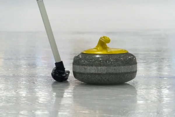 Brush and yellow Curling stone on the ice — Stock Photo, Image