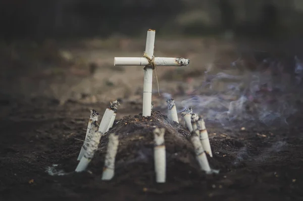 Symbolic grave of tobacco and a cross of cigarettes — Stock Photo, Image