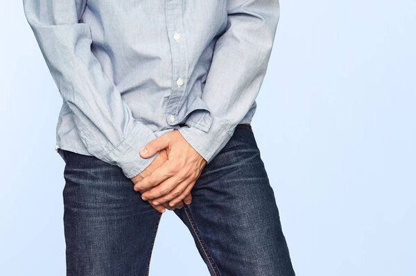 Close up of a man with hands holding his crotch