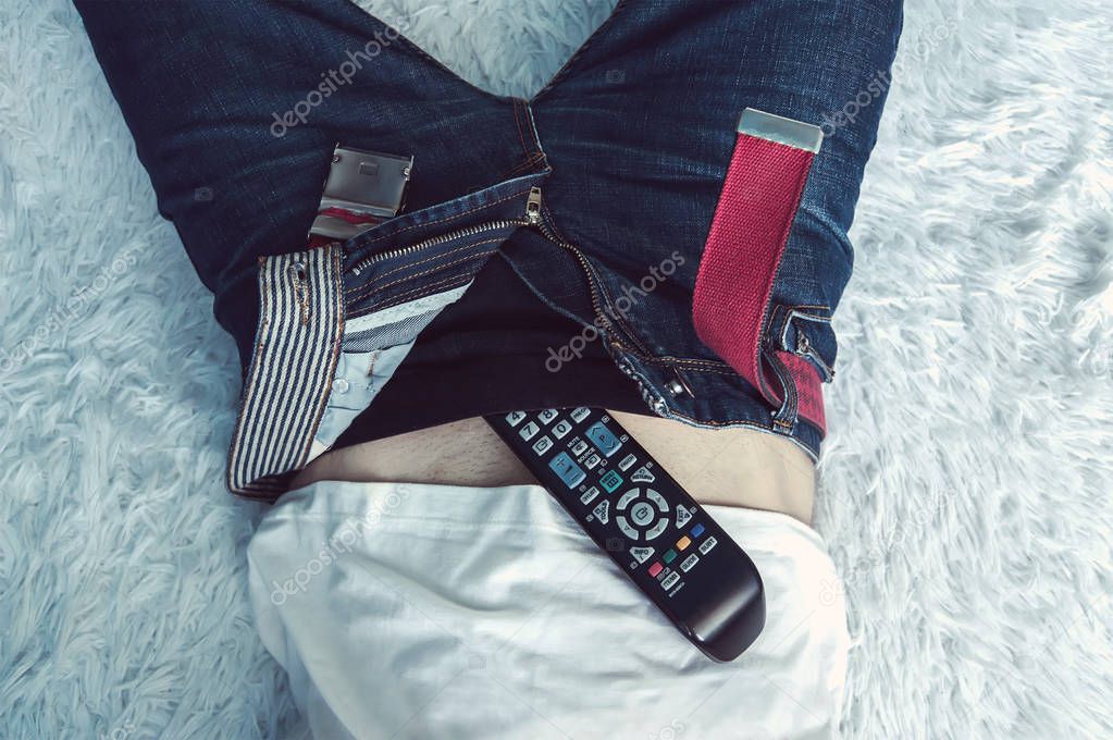 Man lying in bed and watching TV with the TV remote