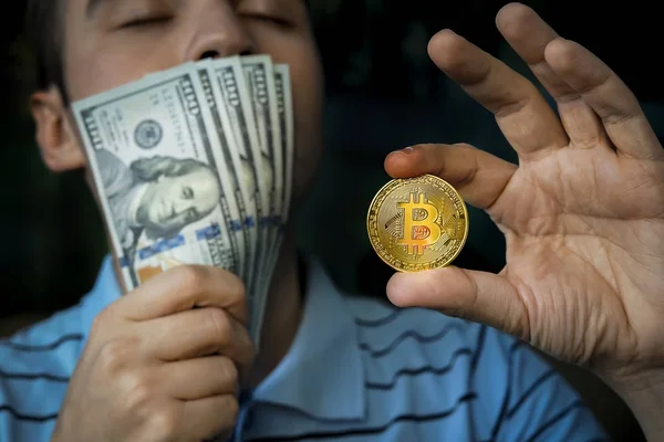 Tipo sosteniendo la moneda bitcoin y dinero en la mano . — Foto de Stock
