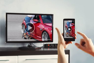 Closeup smartphone ve kullanım uzaktan kumanda ile bir app tutan kadın el üzerinde.