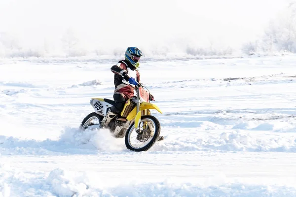 racer on a motorcycle rides in turn of wheels a spray of snow