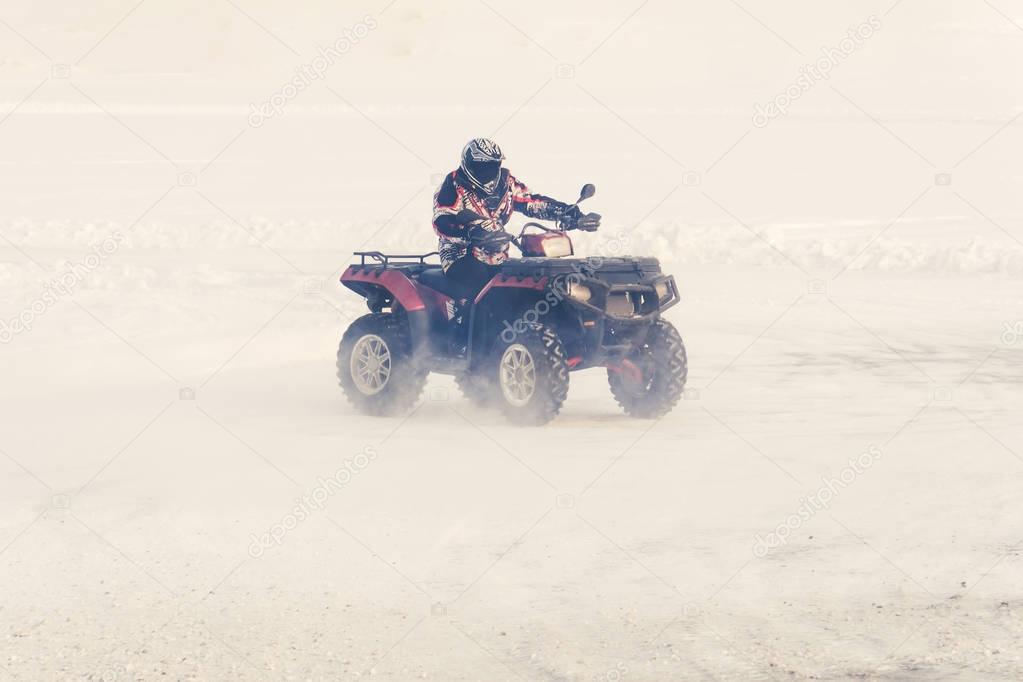 man driving a quad bike in the winter field
