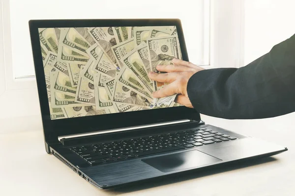 Guy or businessman holding buck money in his hand. Laptop in the background