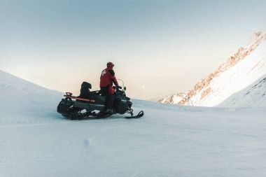 Dağlarda adam cankurtaran kar arabası rides.
