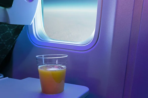 Una tazza di succo d'arancia su vassoio a posto di cabina di un aereo . — Foto Stock