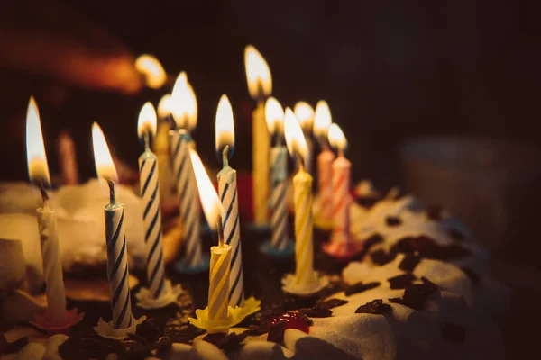 Torta anniversario con candele accese a mano al buio — Foto Stock