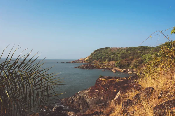 Den branta klippiga kusten med blå havet och vågorna kraschar på klipporna. Indien — Stockfoto