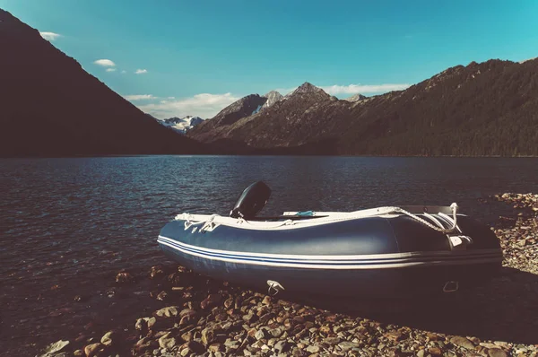 Inflatable boat with motor on the bank of a mountain river