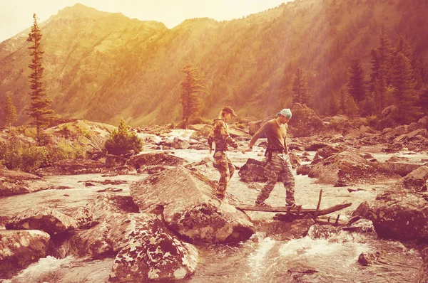 Τουρίστες τύπος και το κορίτσι πάει πάνω από το ποτάμι βουνό, κρατώντας τα χέρια. — Φωτογραφία Αρχείου