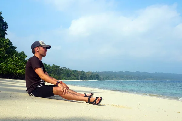Mężczyzna siedzący na tropikalnej plaży patrząc na Oceanie. — Zdjęcie stockowe