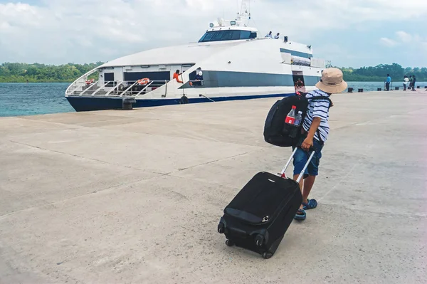 Un hombre camina sobre un muelle llevando una maleta — Foto de Stock