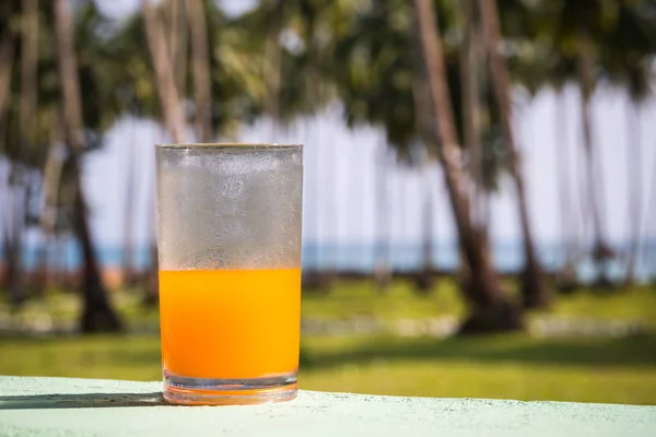 Стакан апельсинового сока на пляжном столе — стоковое фото