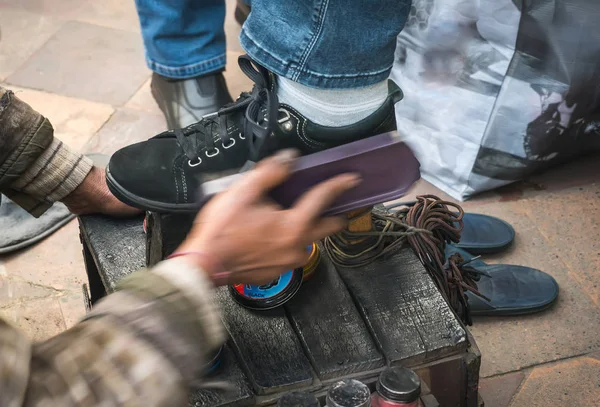 Человек чистки обуви клиента на тротуаре города . — стоковое фото