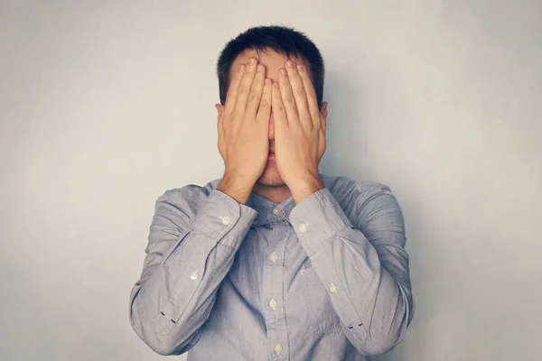 Businessman covers his face with hands. Fatigue and stress at work. The young man covered his eyes with his hands. stop seeing. Hide face.